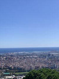 Aerial view of city by sea against clear blue sky