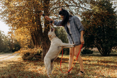 Happy woman plays with her labrador puppy outdoors.