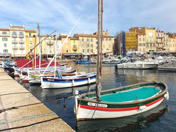 Boats moored in harbor against buildings in city