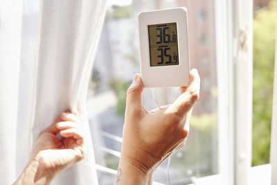 Woman holding thermostat at home