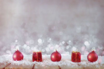 Close-up of baubles with fake snow and christmas presents on table