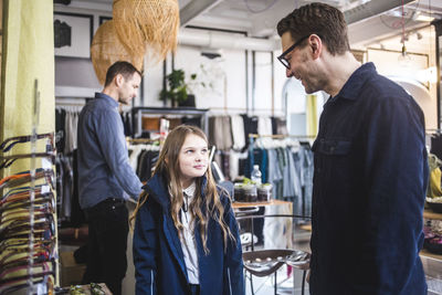 Smiling father wearing eyeglasses while looking at cute daughter in boutique