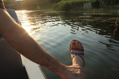 Cropped hand of man holding woman leg in boat on lake