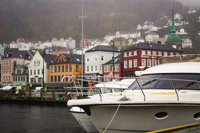 Sailboats moored on river by buildings in city