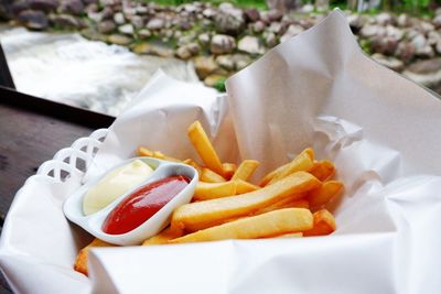 Close-up of french fries and sauce in paper