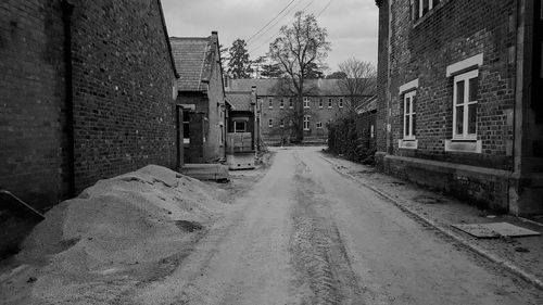 Empty road amidst buildings against sky