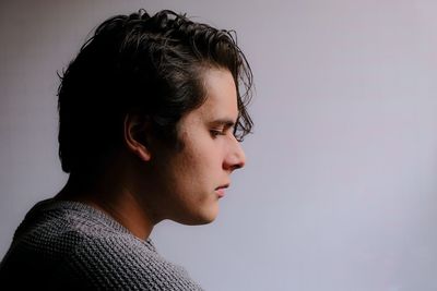 Thoughtful young man looking away against white background