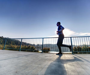 Full length of woman standing on railing against sky