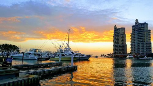 Boats moored at harbor against sky during sunset