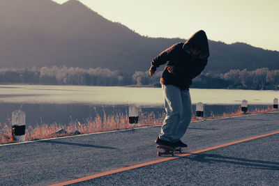 Rear view of man standing by lake during sunset