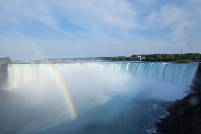 Scenic view of rainbow over river against sky