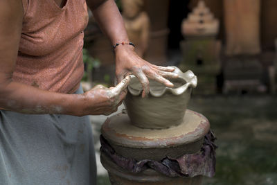 Midsection of woman working on pottery wheel