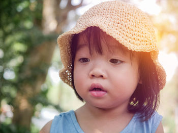 Close-up portrait of cute baby girl looking away outdoors