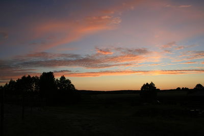 Silhouette trees on field against sky during sunset