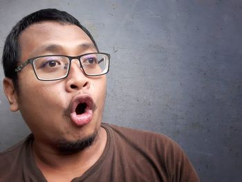 Portrait of young man wearing eyeglasses against wall
