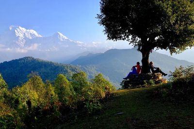 People sitting on mountain against sky