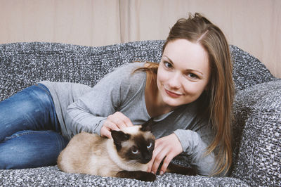 Portrait of woman with cat lying on sofa at home