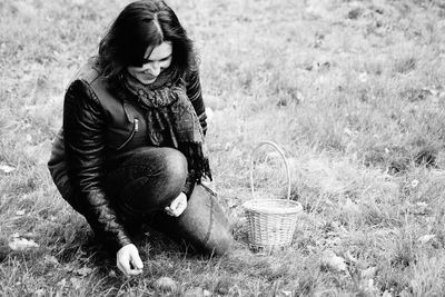 Young woman sitting in basket on field