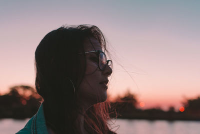 Close-up of young woman against sky during sunset