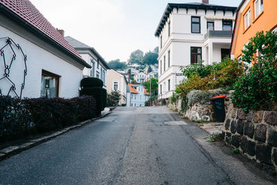 Narrow street amidst houses against clear sky