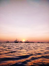 Sailboats sailing in sea against sky during sunset