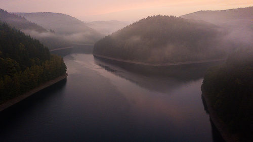 Scenic view of river by mountains against sky during sunset