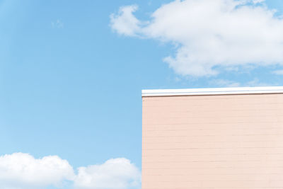 Low angle view of pink building against blue sky with clouds and minimalism.