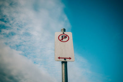 Low angle view of road sign against blue sky