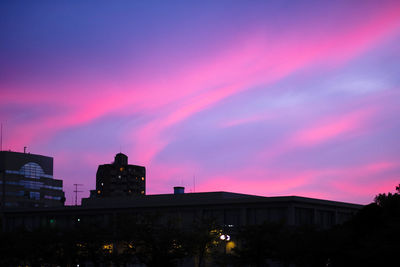 Silhouette buildings against dramatic sky during sunset