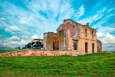 Old house on field against sky