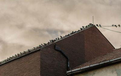 Low angle view of roof against cloudy sky