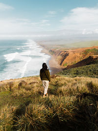 Rear view of man looking at sea against sky