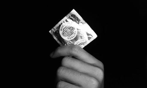 Close-up of hand holding paper against black background