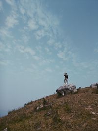 Man standing on rock against sky