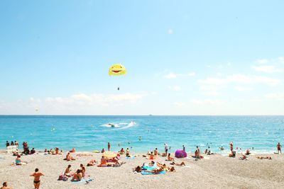 People on beach against clear blue sky