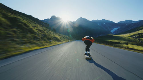 Rear view of man riding bicycle on road