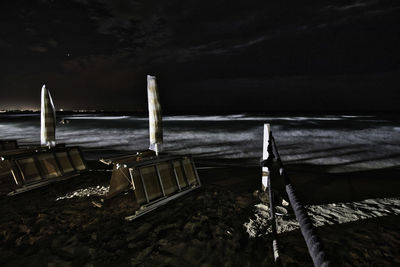 Deck chairs on beach against sky at night