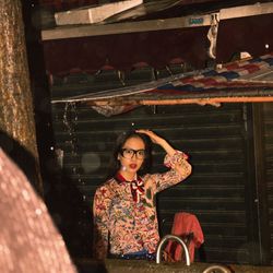 Portrait of young woman standing below roof during rain at night