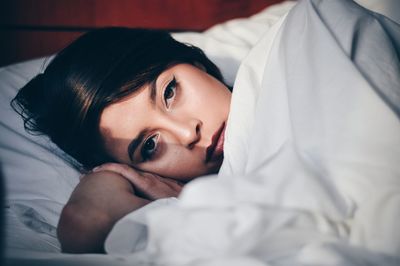 Close-up portrait of young woman lying on bed