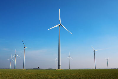 Windmills on field against sky