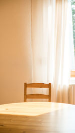 Empty chair and table against wall at home