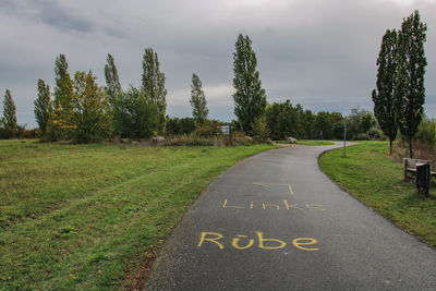 Road amidst trees and plants against sky