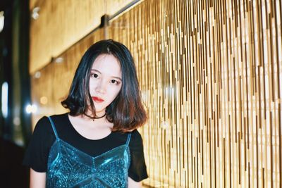 Portrait of young woman standing by tiled wall