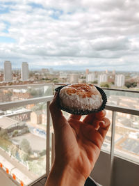 Midsection of person holding ice cream against cityscape