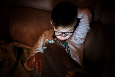 Boy using mobile phone on sofa at home