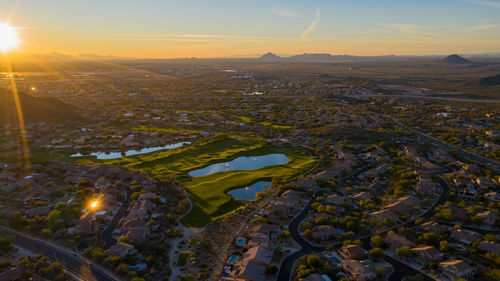 Aerial view of illuminated city buildings against sky during sunset