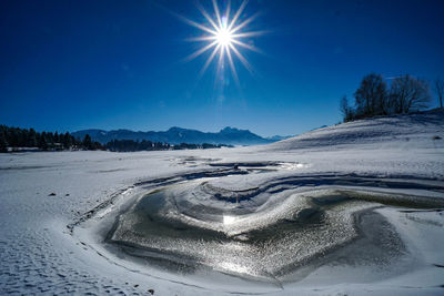 Scenic view of snowcapped landscape against blue sky