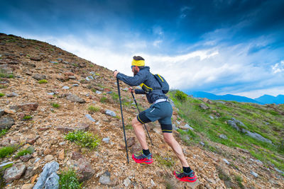 Man climbing on mountain against sky