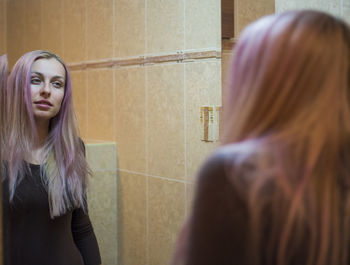 Young woman with long hair reflecting on mirror