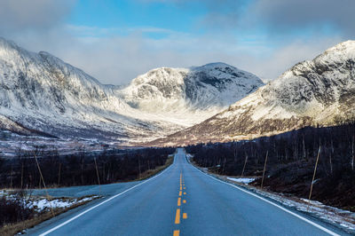 Road amidst snowcapped mountains of norway against sky